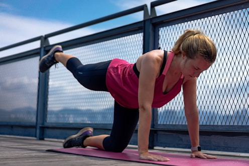 woman in red tank top and black leggings doing yoga