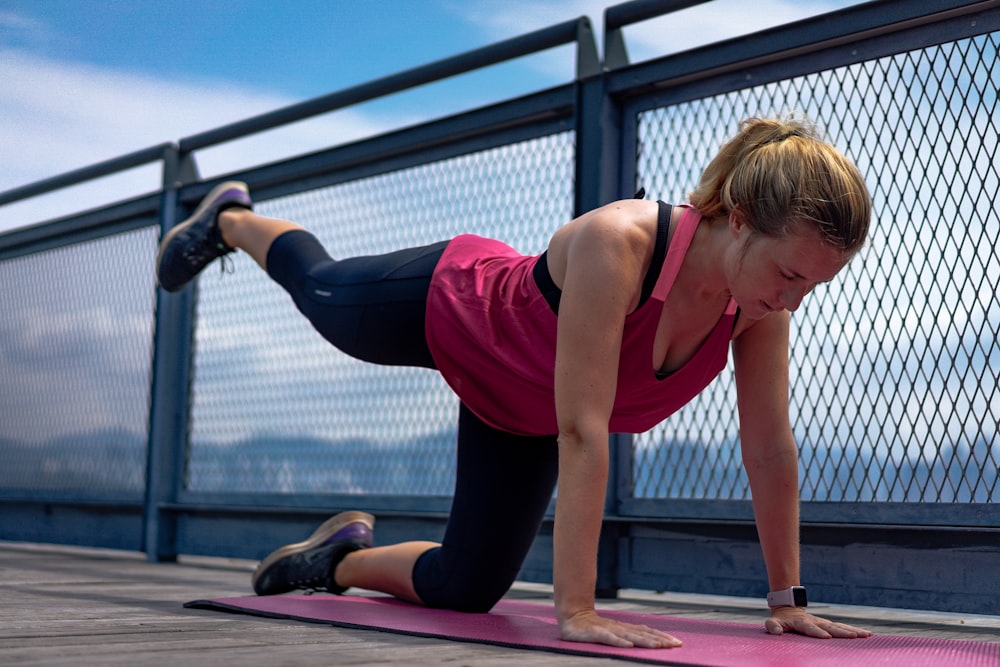 woman in red tank top and black leggings doing yoga