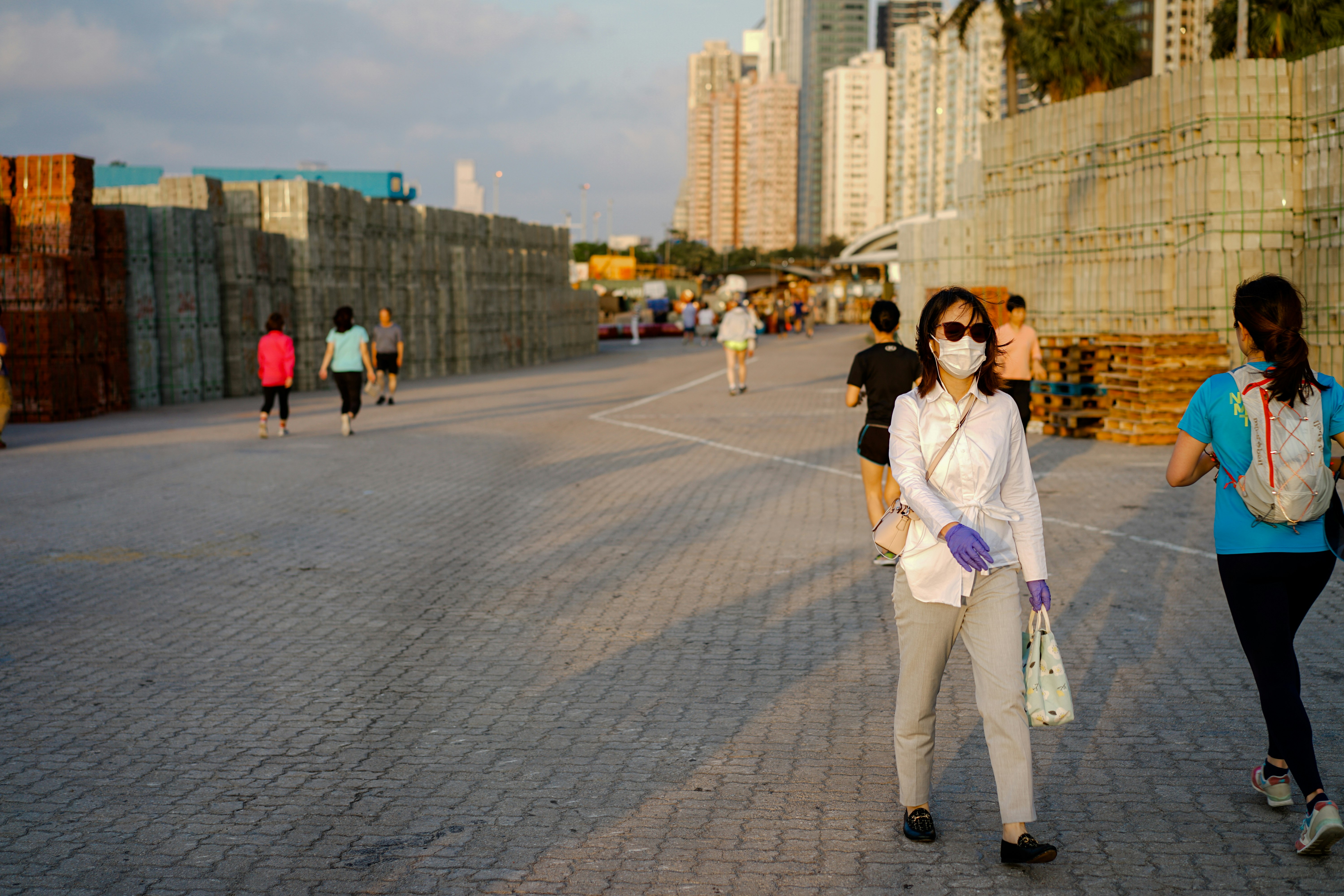 woman in white long sleeve shirt and white pants standing on gray concrete pavement during daytime