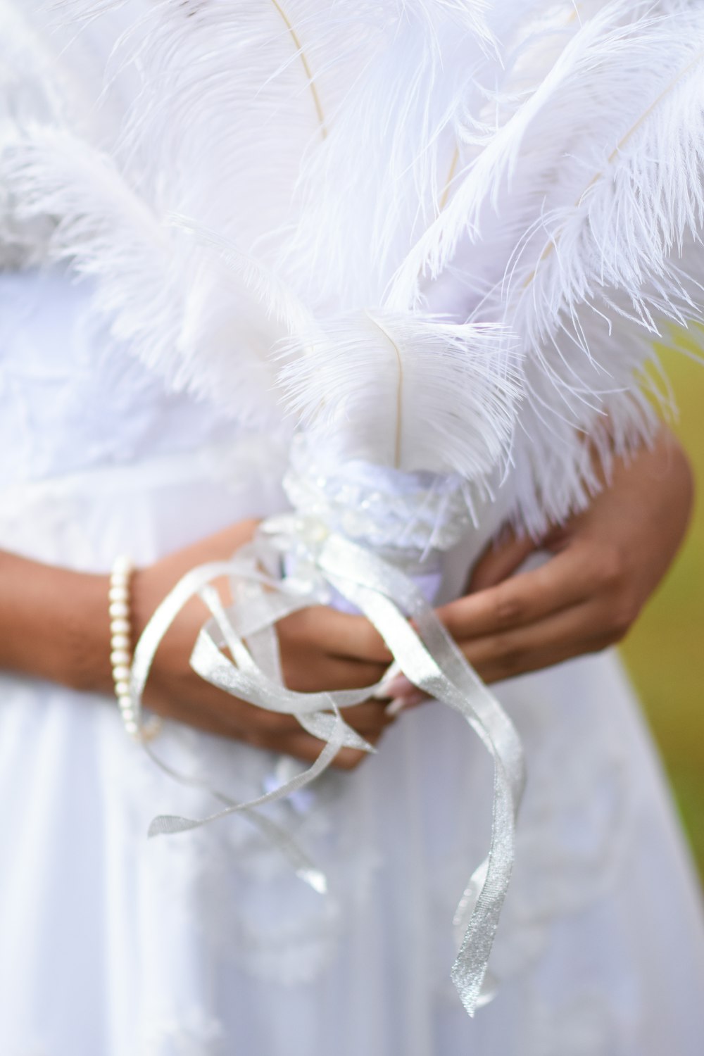 person holding white feather on white textile