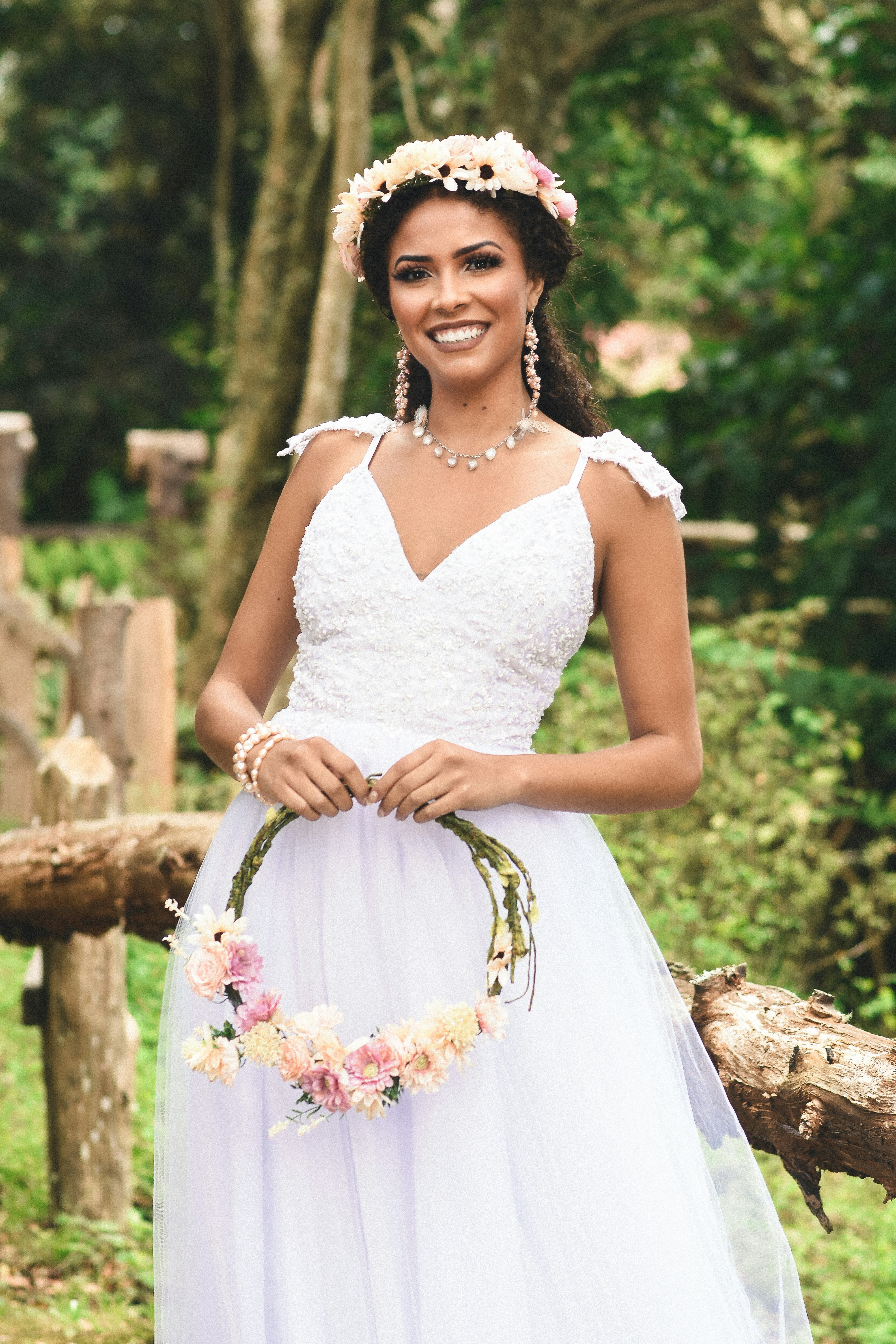 Woman in white floral wedding dress standing near brown wooden fence ...