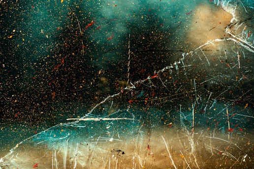 An abstract composition featuring shattered glass and splatters of vibrant colors, possibly resembling a cosmic space with nebulous swirls and scattered debris.