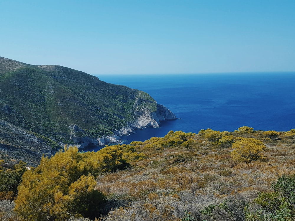 green mountain beside body of water during daytime