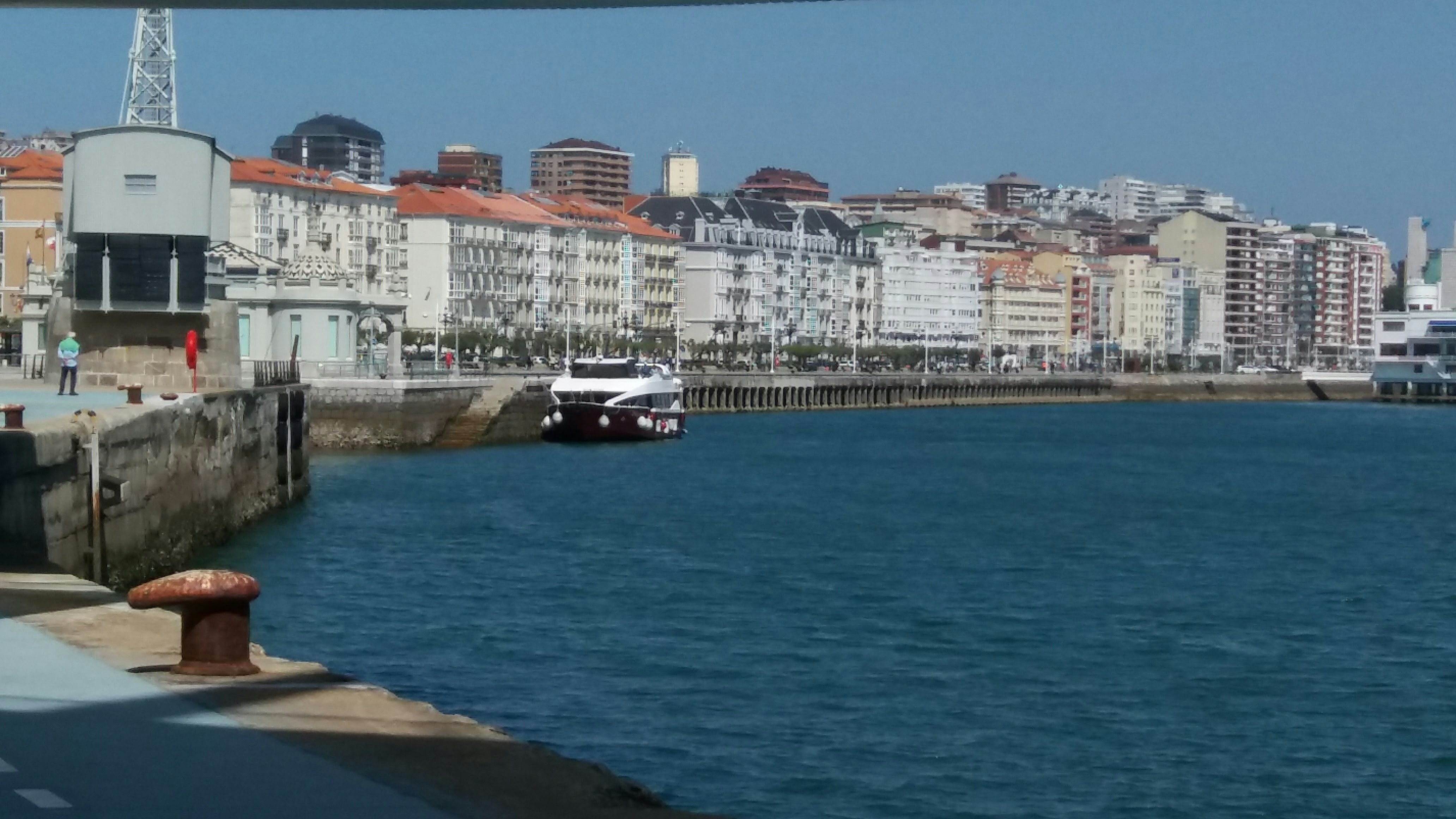 white and black boat on sea near city buildings during daytime