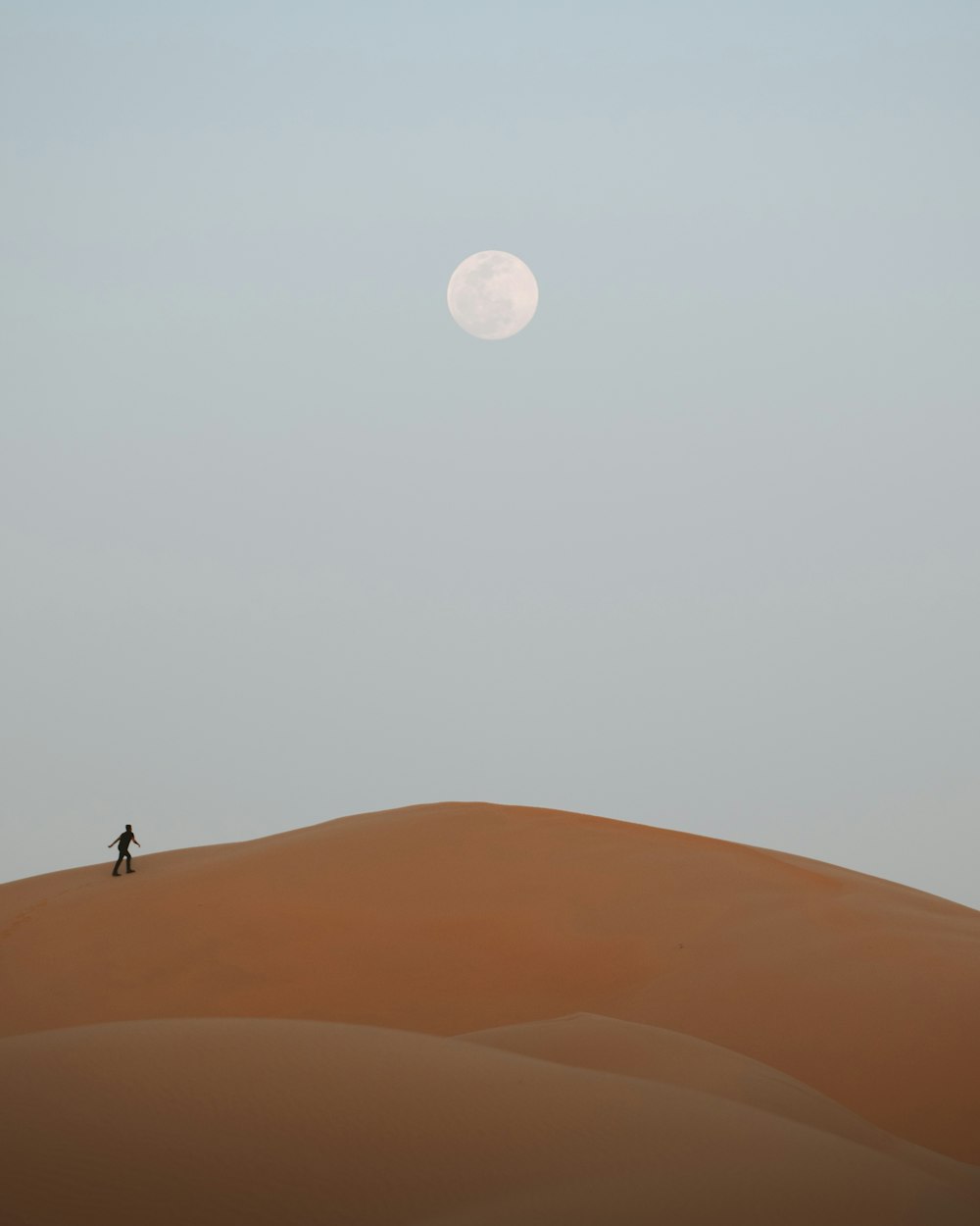 hombre de pie en el desierto bajo la luna llena