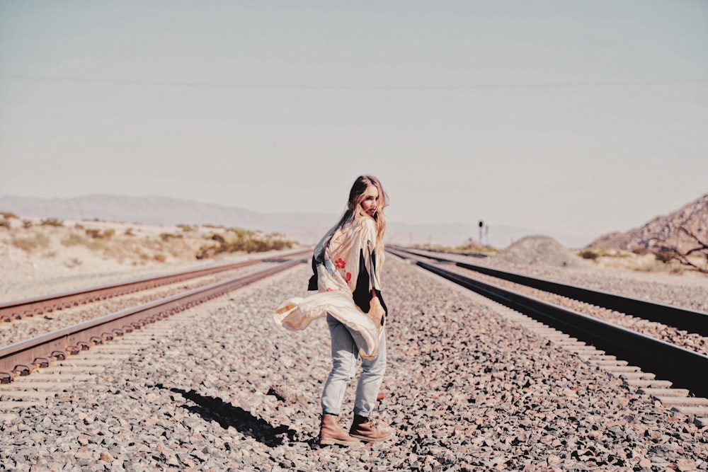 woman in white long sleeve shirt and blue denim jeans standing on road during daytime