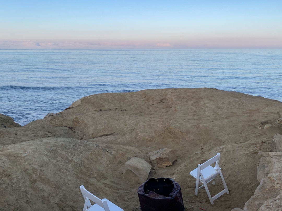 a couple of white chairs sitting on top of a rocky beach