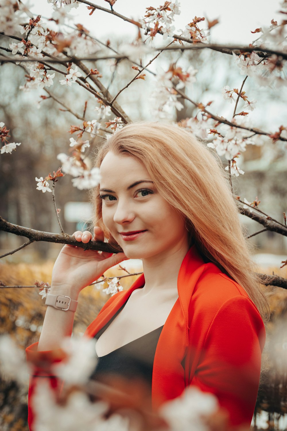 woman in red blazer holding white flowers