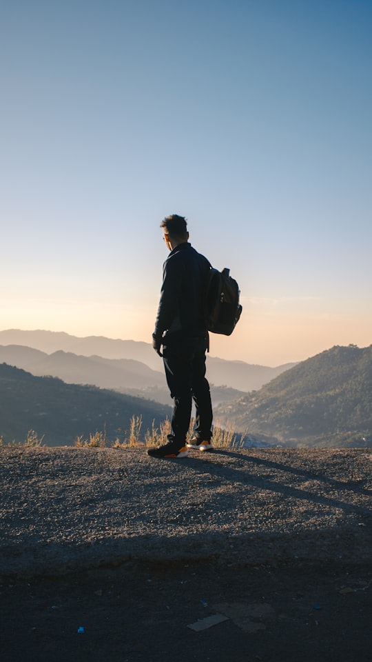 man in black jacket standing on top of mountain during daytime in Uttarakhand India
