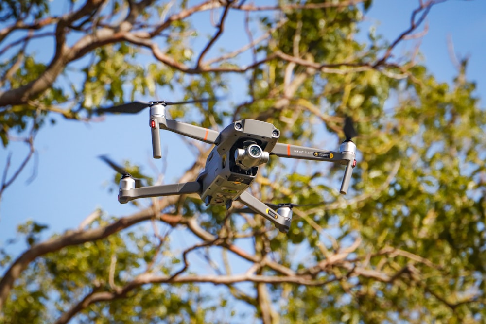 black and gray drone flying over the tree