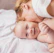 A smiling mother cuddling her baby in cozy, stylish clothing from Mummy and Kids Collection, set against a softly lit, futuristic dark background.