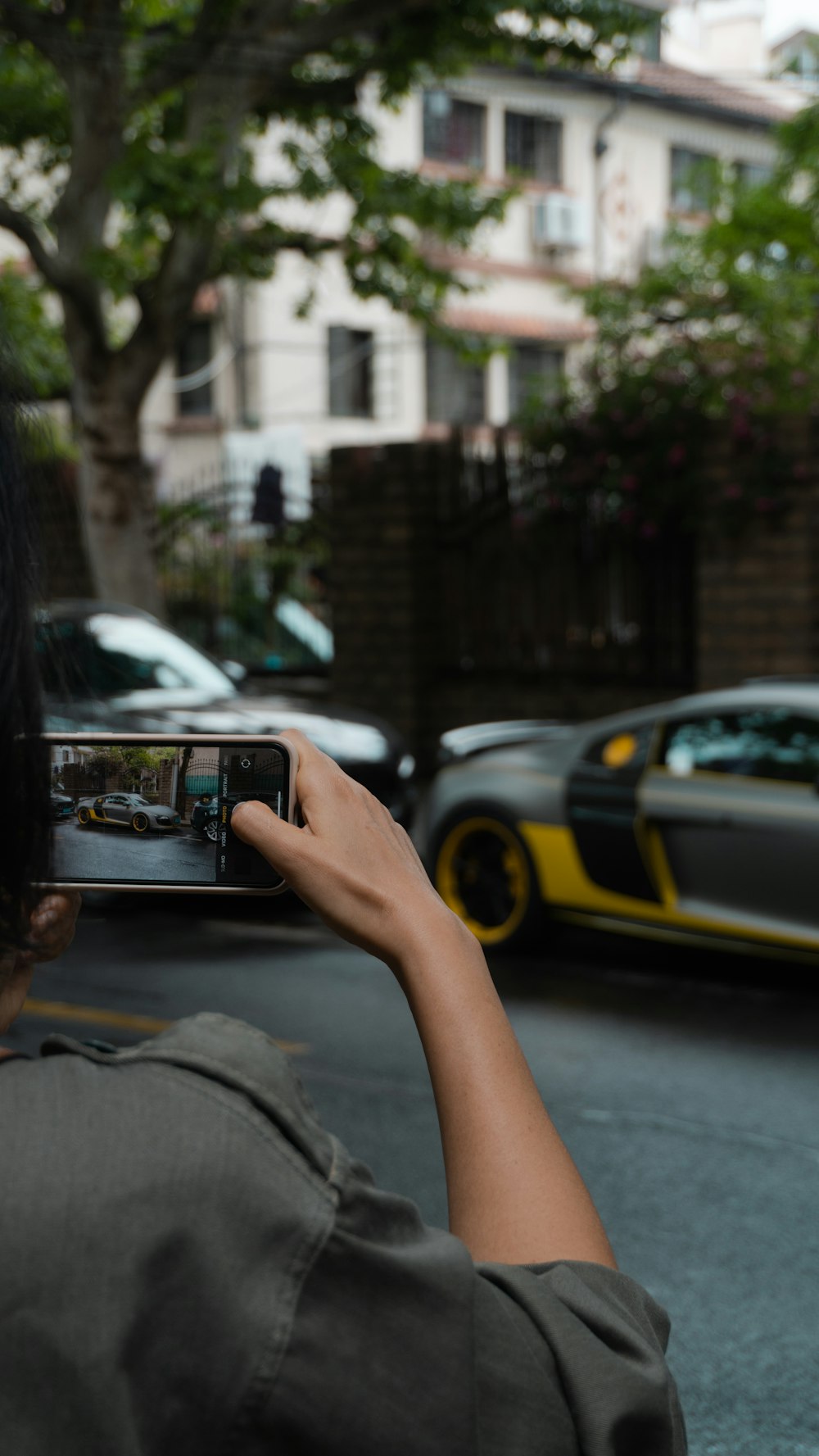 person holding black smartphone taking photo of cars on road during daytime