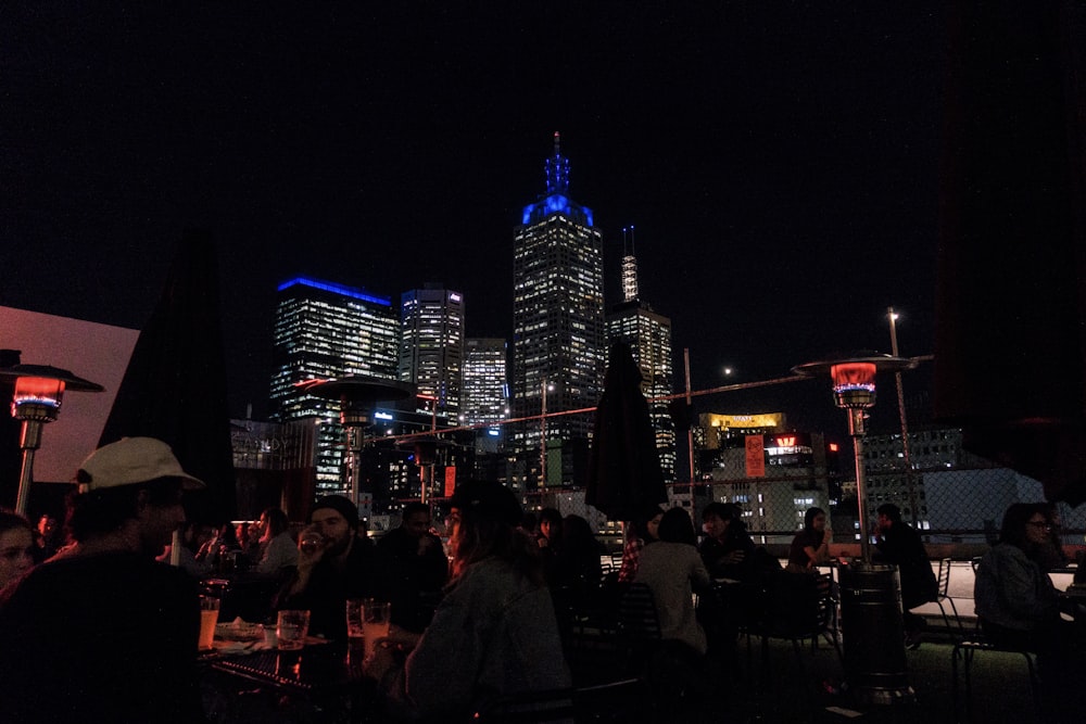 people sitting on chair near high rise buildings during night time