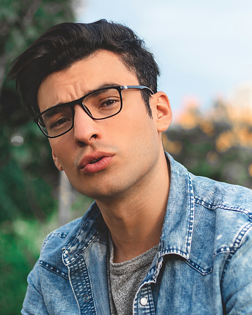 man in blue denim jacket wearing black framed eyeglasses