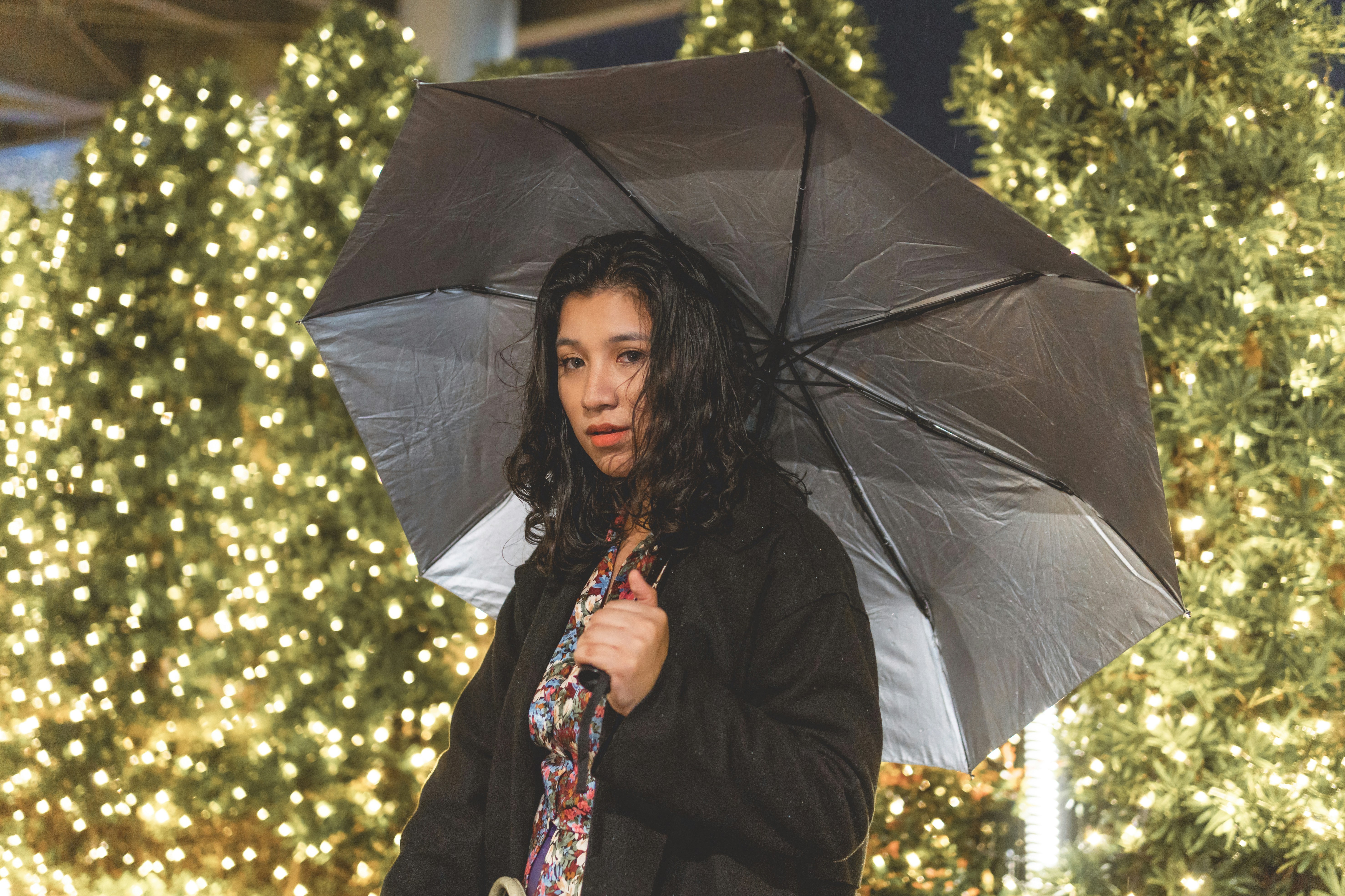 Frau im schwarzen Mantel mit Regenschirm