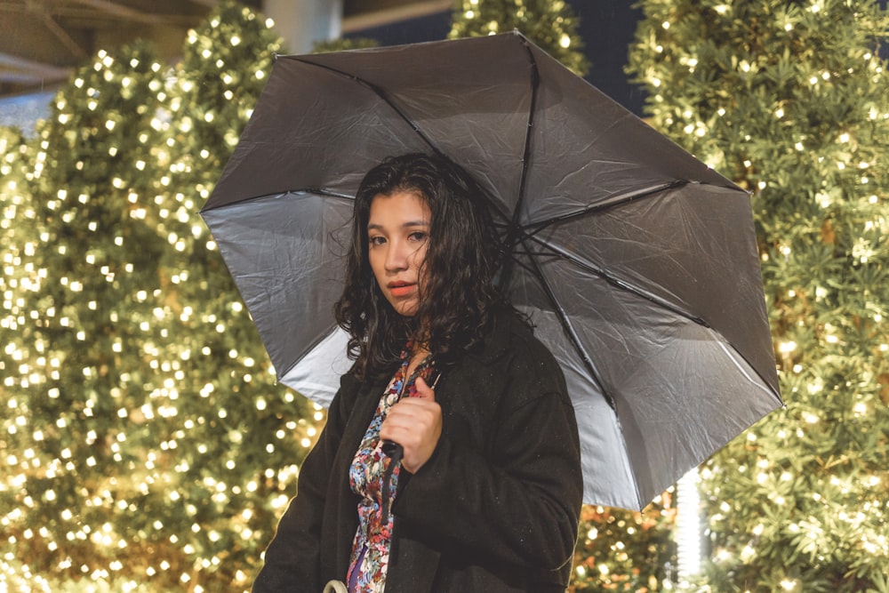 woman in black coat holding umbrella