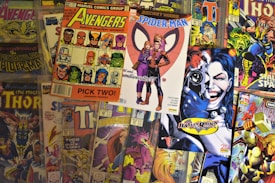 A collection of colorful comic book covers featuring popular characters such as the Avengers, Spider-Man, Thor, and Harley Quinn. The comics are arrayed in a slightly overlapping manner, displaying vibrant artwork and various superhero poses.