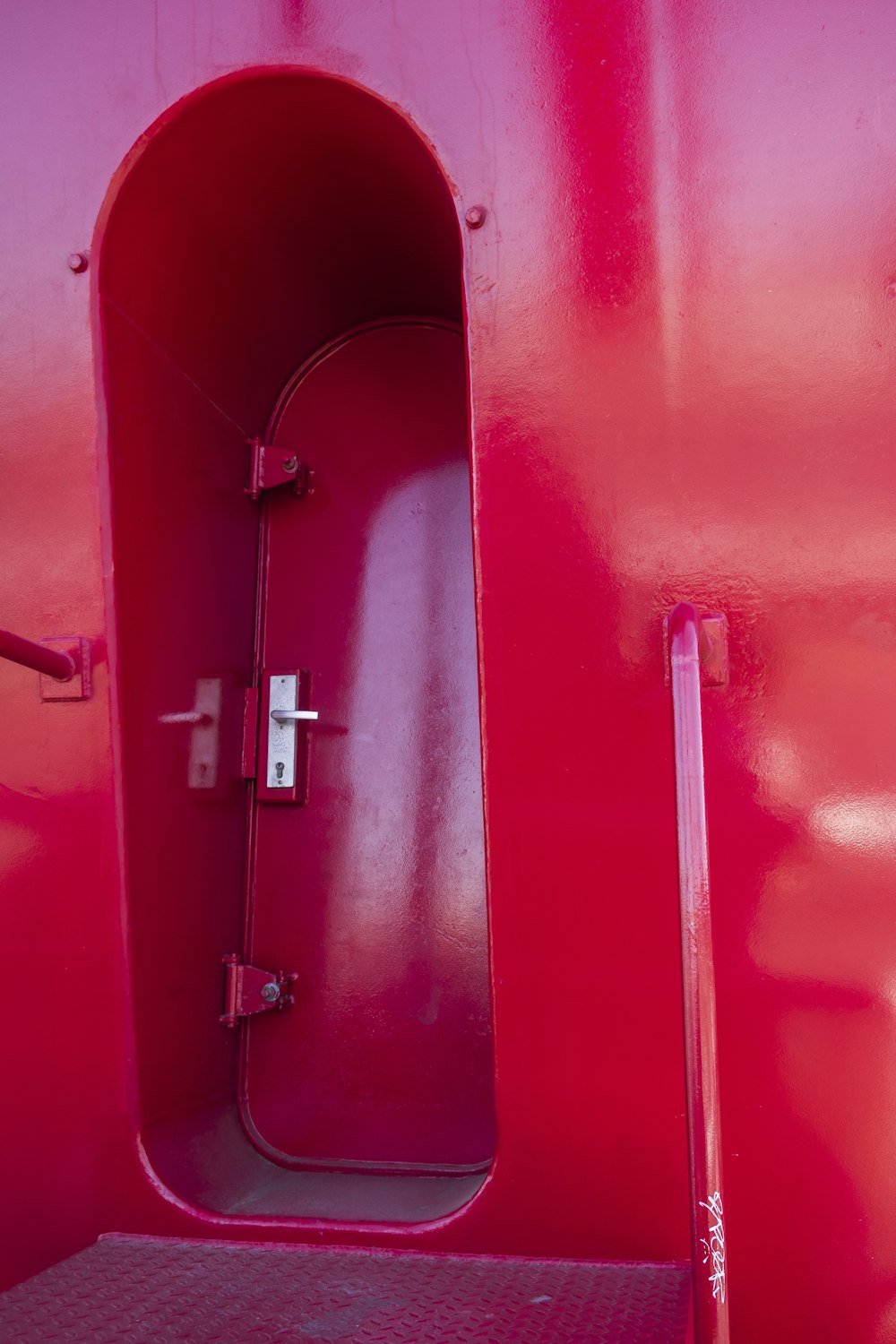 Puerta de madera roja con palanca plateada