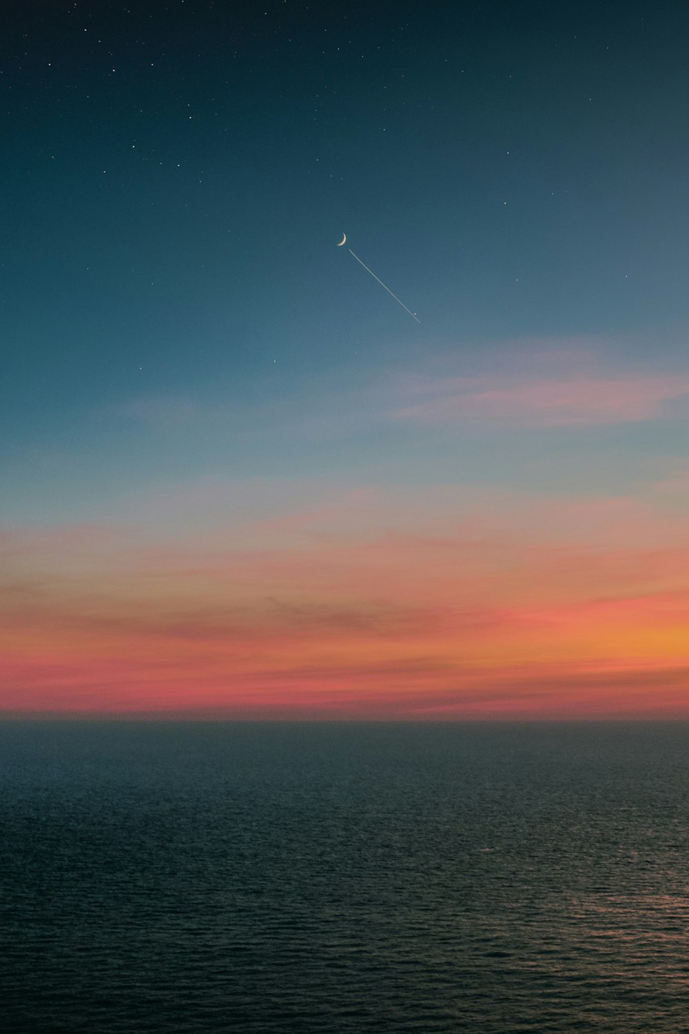 body of water under orange and blue sky