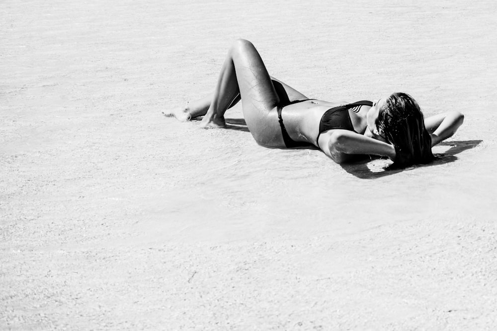 woman in black bikini lying on sand