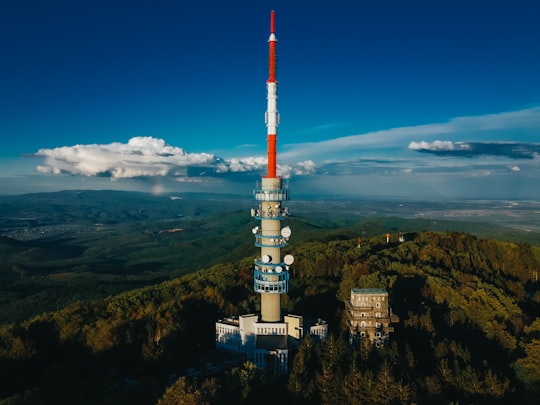 white and red tower on top of mountain under blue sky during daytime in Gyöngyös Hungary