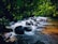 Close-up of a handcrafted stone waterfall feature surrounded by lush greenery under soft lighting.