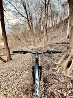 Close-up of mountain bike tires kicking up dirt on a forest path surrounded by autumn leaves.