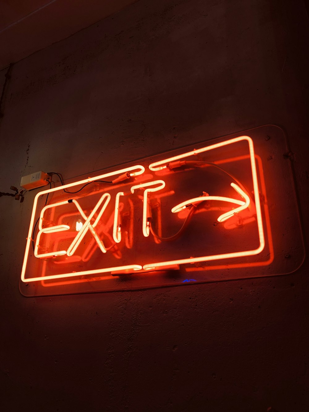 a neon exit sign hanging from the side of a wall