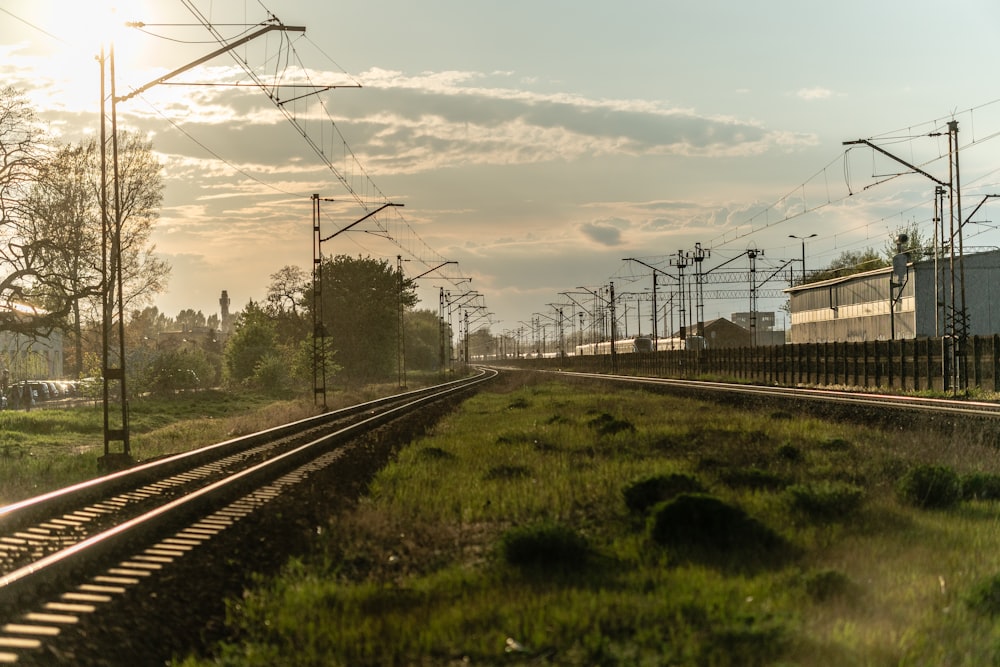 black metal train rail under white clouds and blue sky during daytime