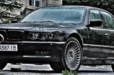 Side view of a luxury sedan freshly detailed, parked on a dark driveway with purple and gold highlights.