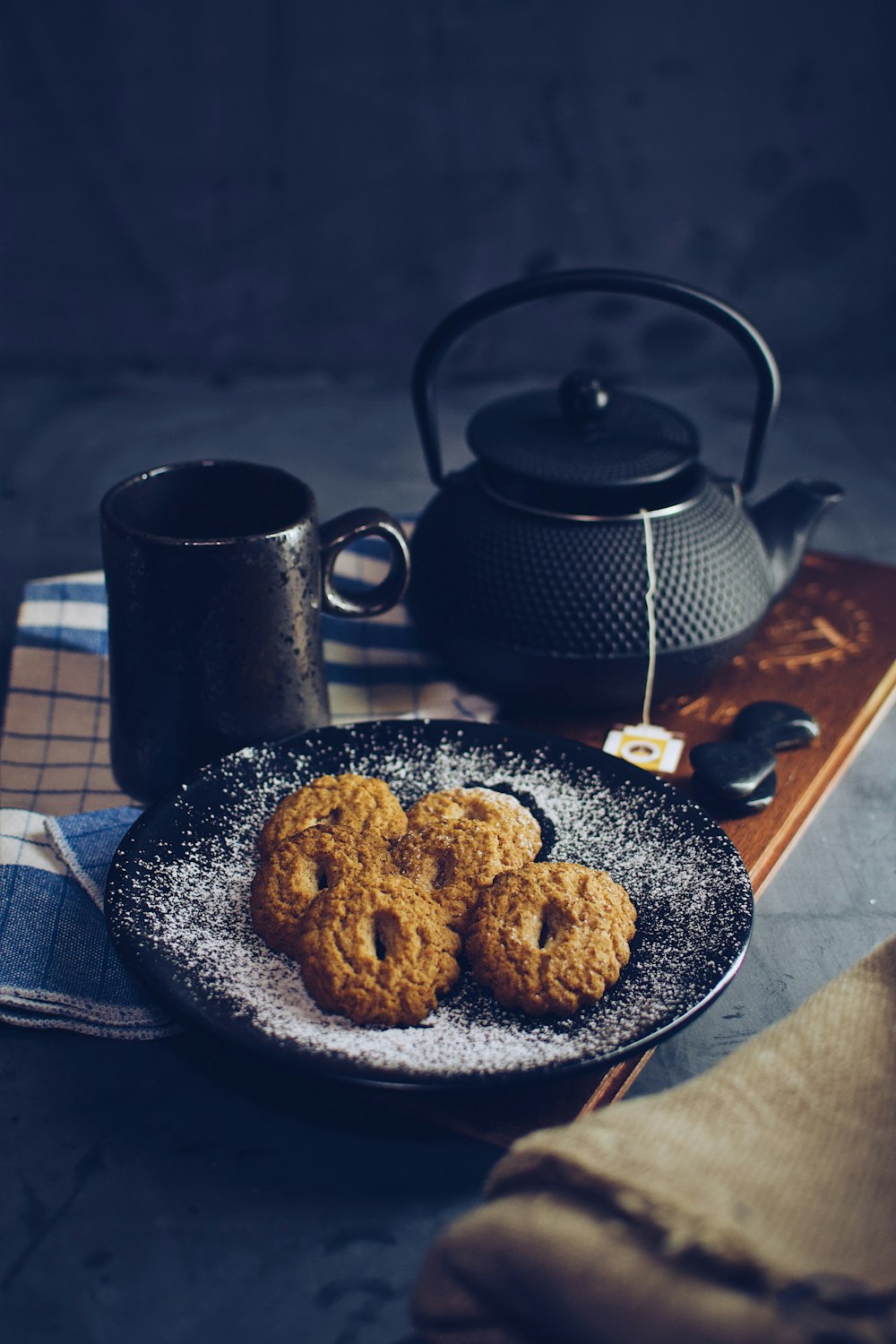 black ceramic mug beside brown cookies on blue ceramic plate