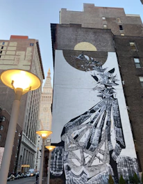 A vibrant city street mural showing a fusion of abstract patterns and urban figures at dusk.