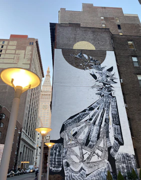 A vibrant city street mural showing a fusion of abstract patterns and urban figures at dusk.