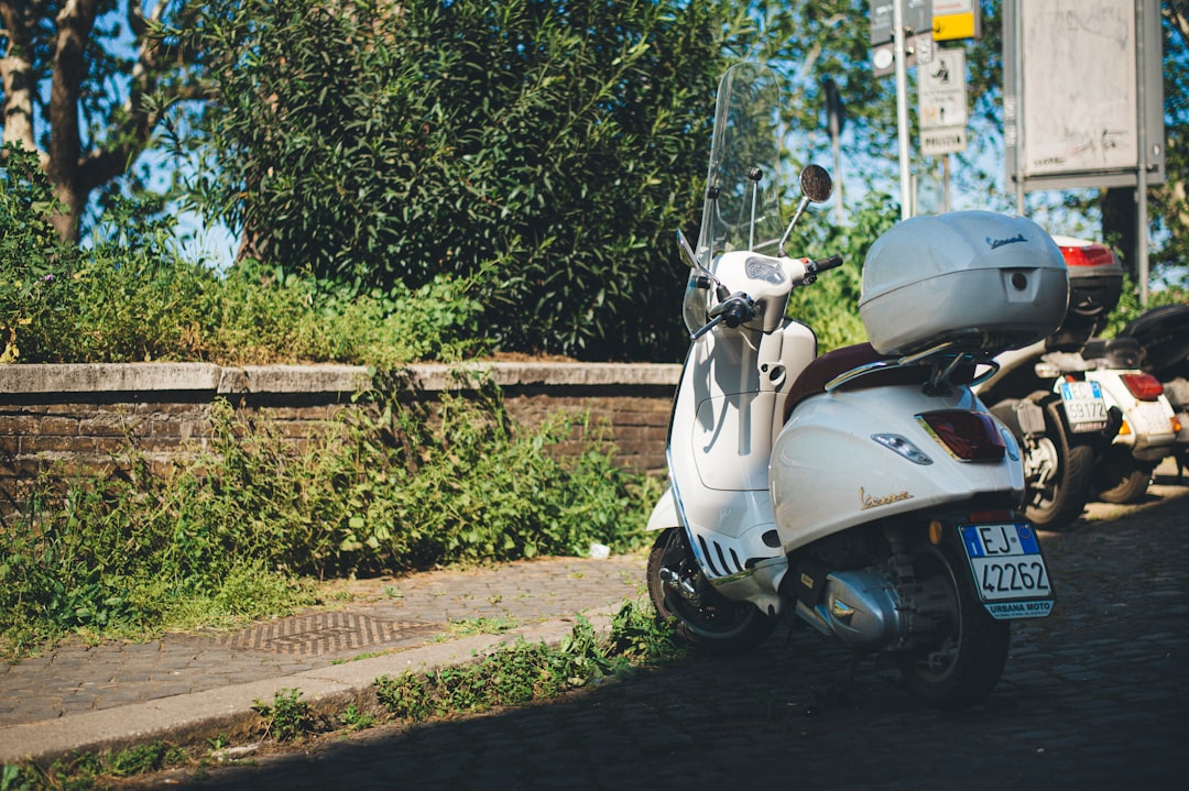 white and black motor scooter parked on brown soil during daytime