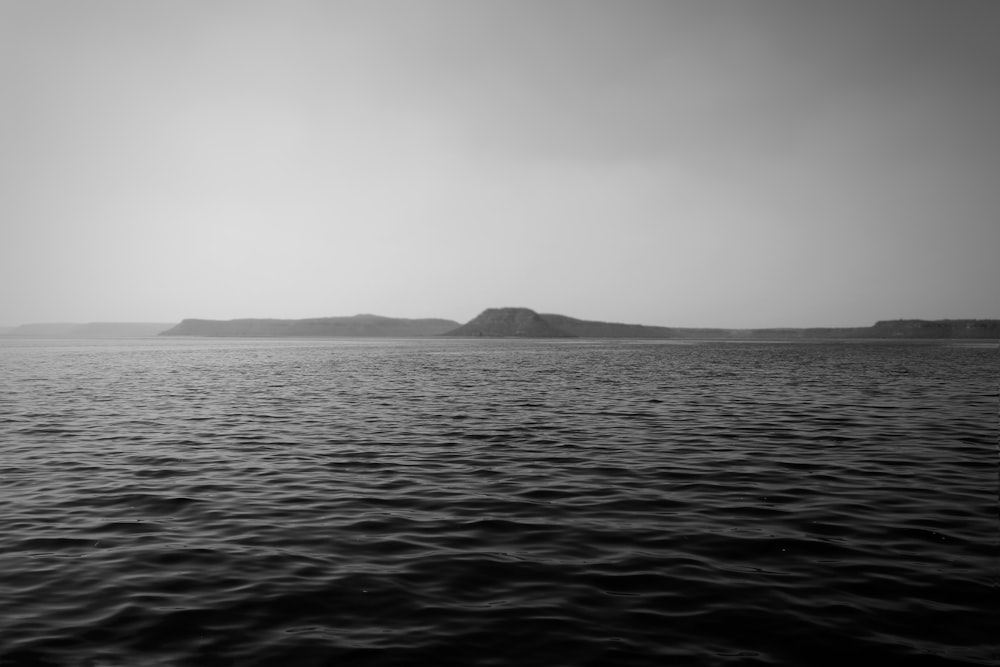 Graustufenfoto eines Berges in der Nähe von Gewässern