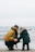 man and woman wearing parka jacket standing on beach during daytime