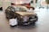 A sleek brown Audi A3 1.8 T quattro is prominently displayed inside a modern showroom. The car has a shiny surface and its stylish design is accentuated by the bright indoor lighting. There is a small informational stand in front of the vehicle, and another car is partially visible in the background, adding depth to the scene. Large windows in the showroom allow natural light to filter through, contributing to the polished and professional ambiance.