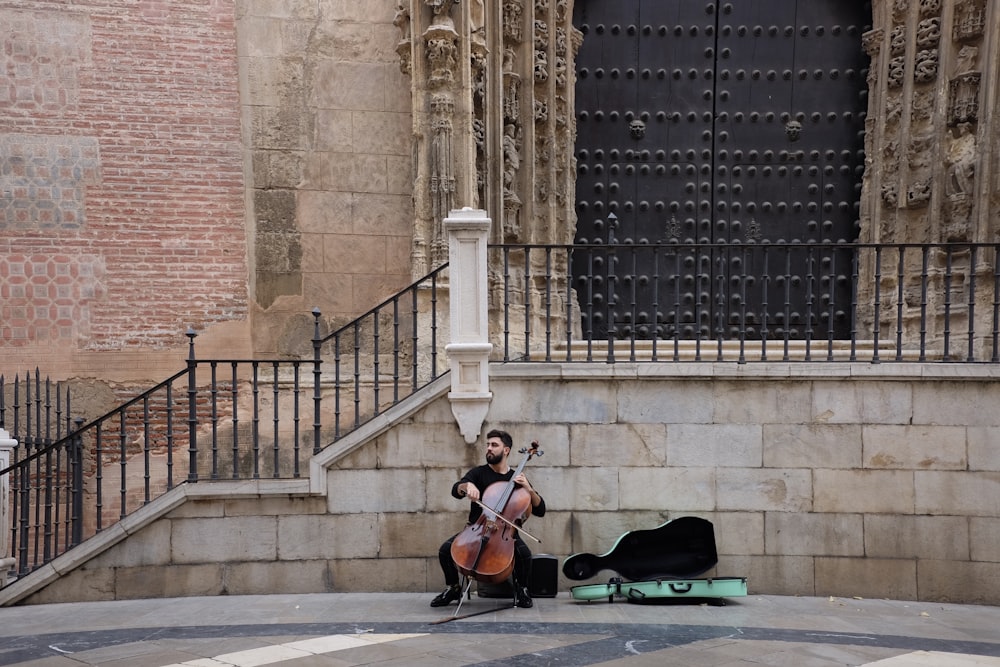 man in brown jacket playing violin near brown concrete building during daytime