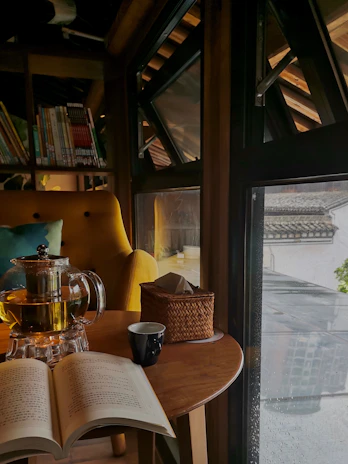 A cozy nook with a stack of colorful handmade journals and a cup of tea on a wooden table.