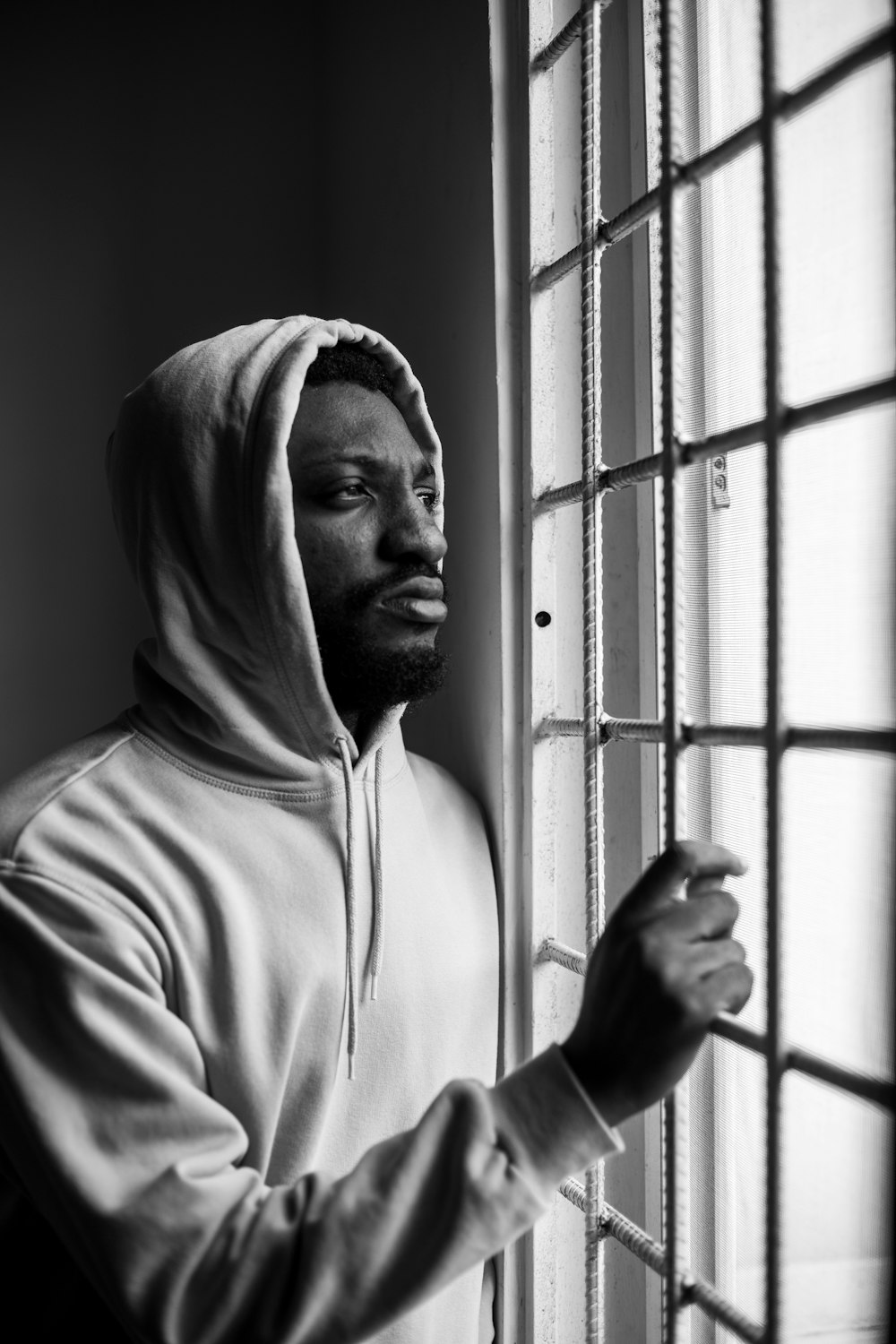 man in white hoodie standing near window