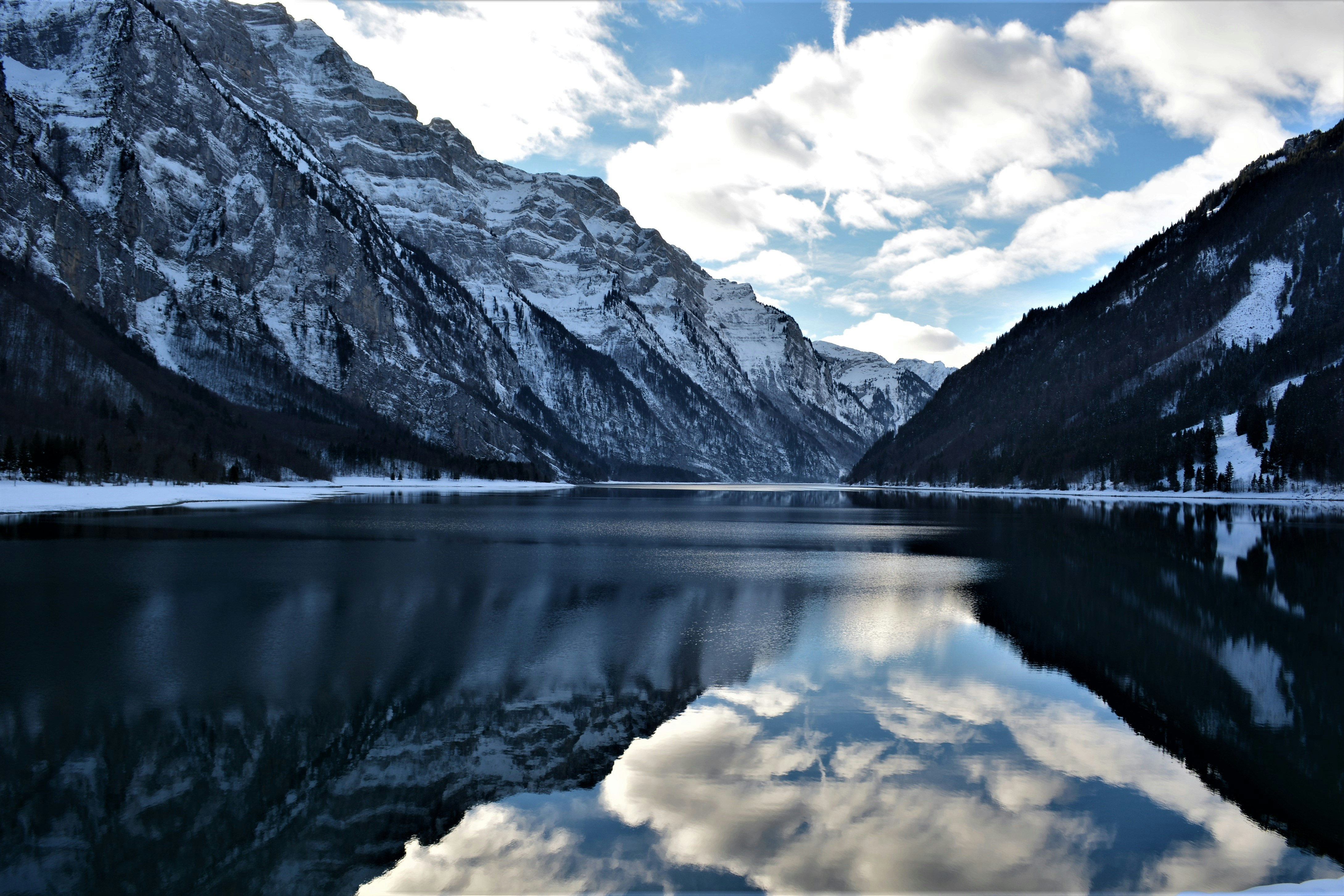 lake near mountain under blue sky during daytime