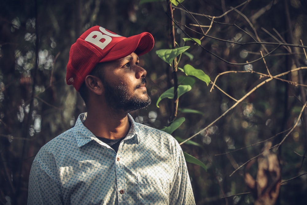 Hombre con camisa abotonada azul y blanca con gorra roja y blanca