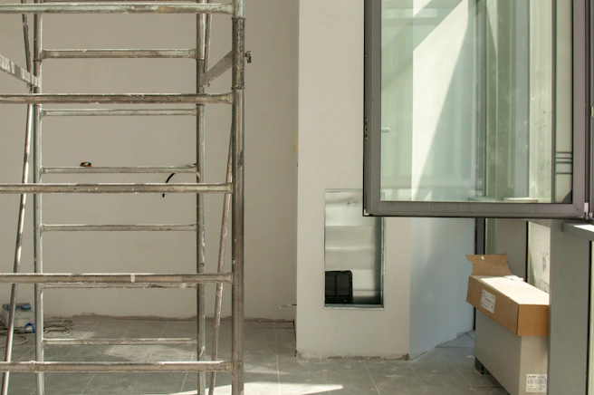 stainless steel ladder leaning on white wall