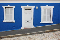 Exterior building facade freshly painted in deep blue and white tones under bright sunlight.
