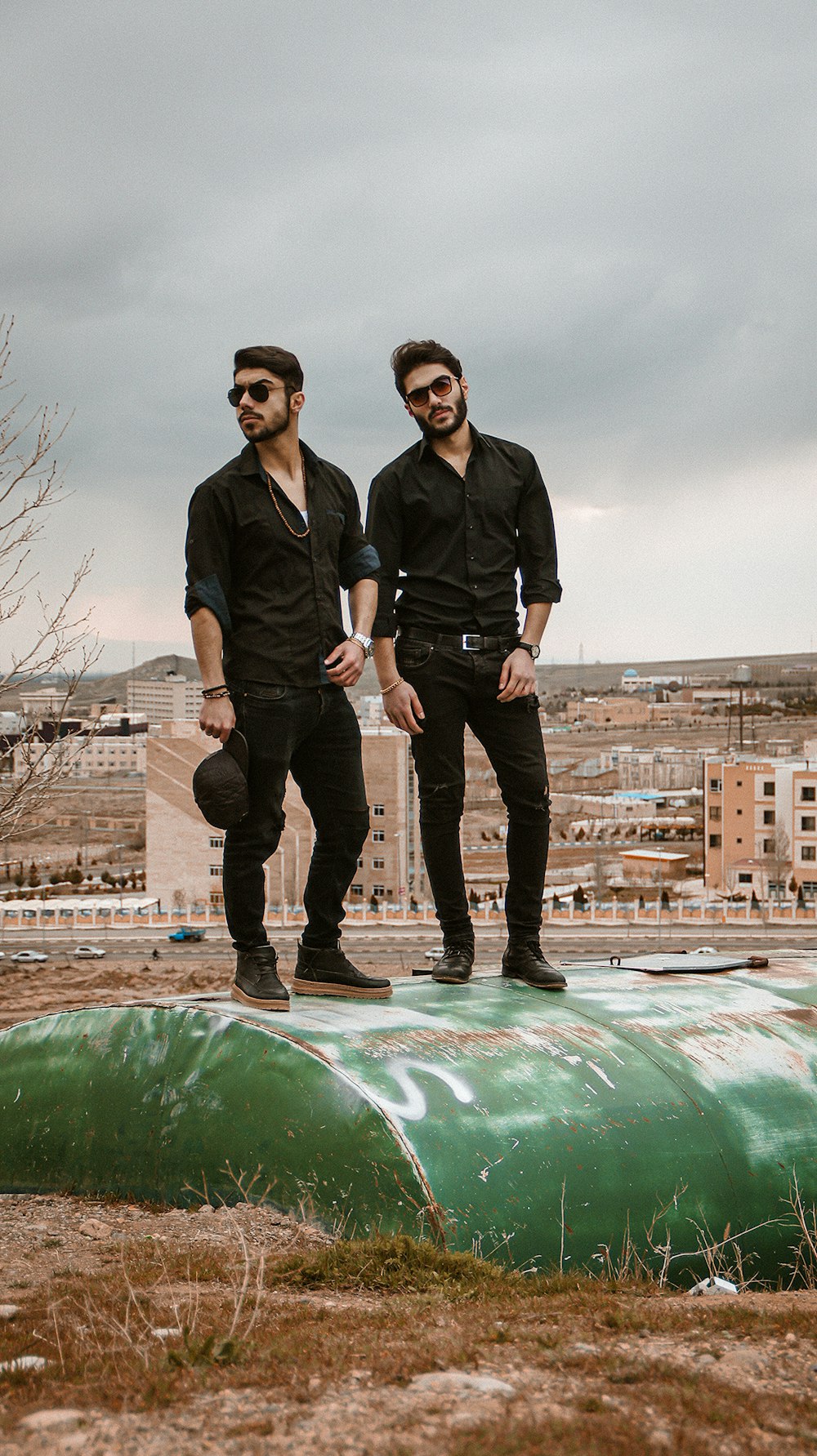 2 men in black jacket standing on green rock during daytime