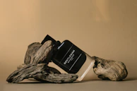 Men’s fragrance bottle standing beside refined personal care products on a dark wood shelf.