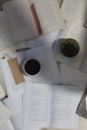 An open Quran on a wooden desk, surrounded by Islamic study materials and a cup of tea.