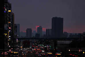 A bustling city street illuminated by evening lights.
