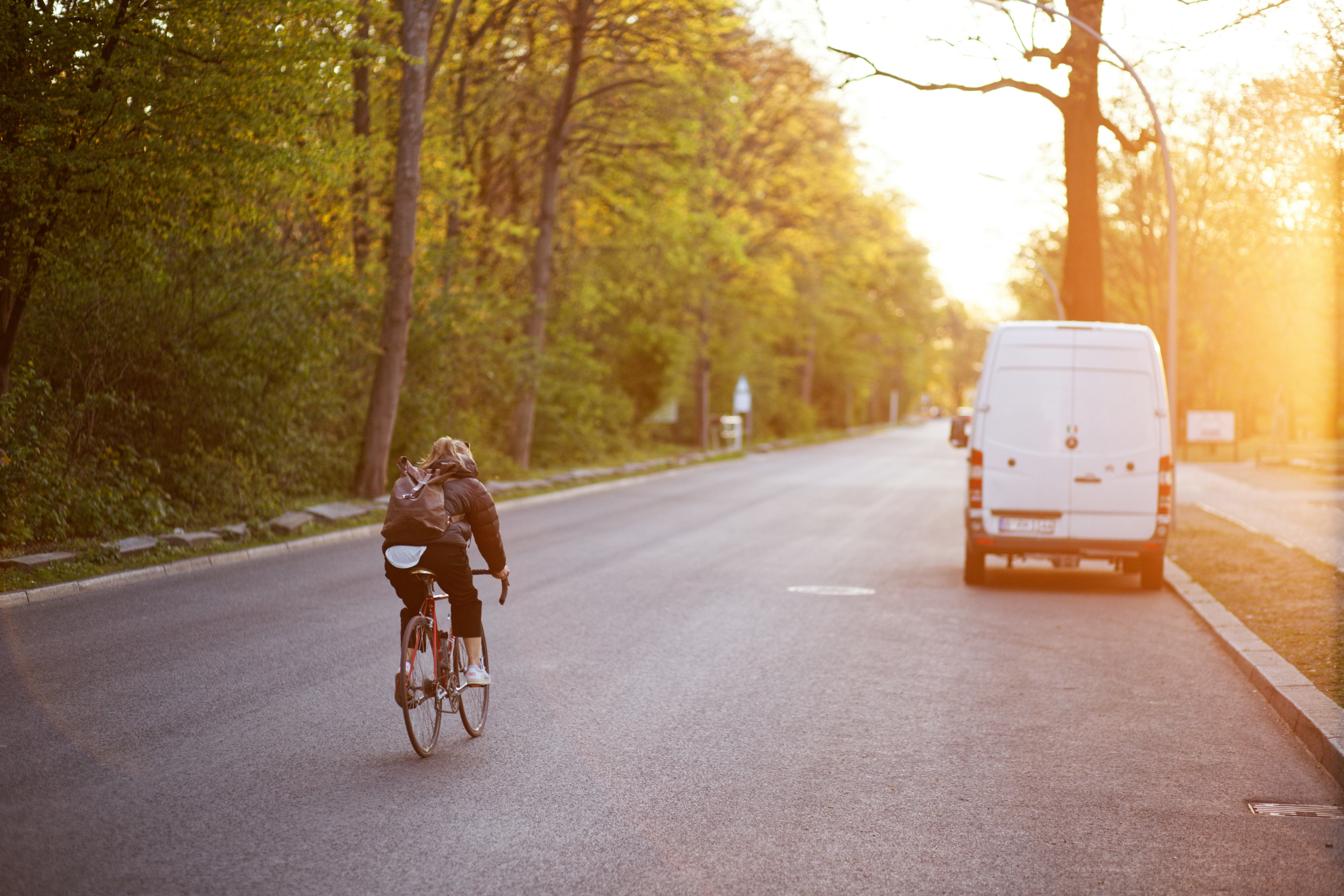 woman in black jacket riding bicycle on road during daytime