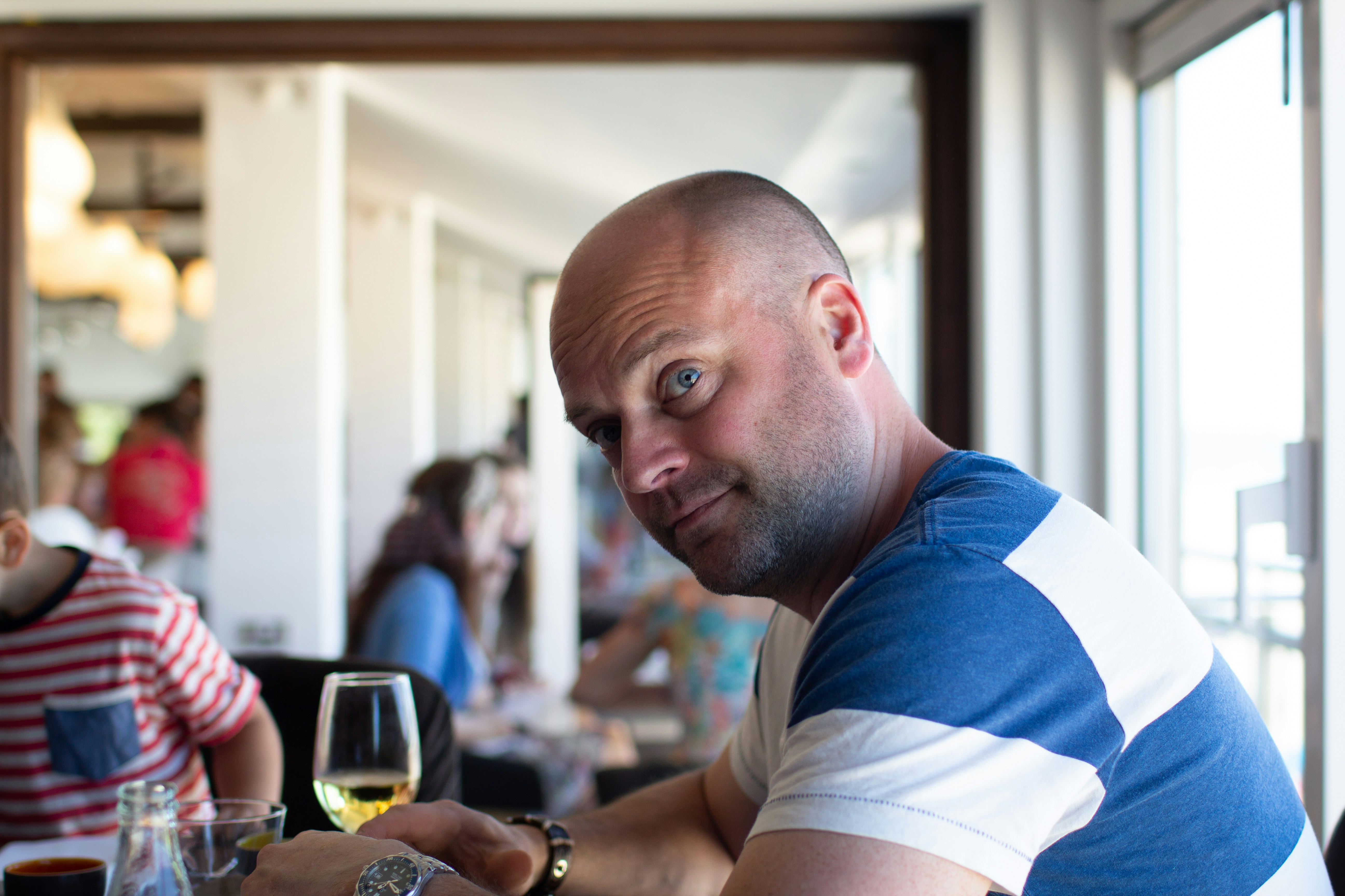 man in blue and white crew neck t-shirt holding clear drinking glass